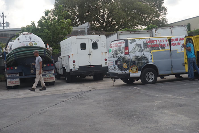 Plumber Mike's septic pump truck and service vans in the yard